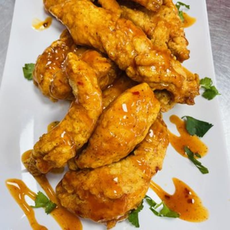 Crispy golden chicken tenders drizzled with a sweet and spicy sauce, garnished with cilantro.