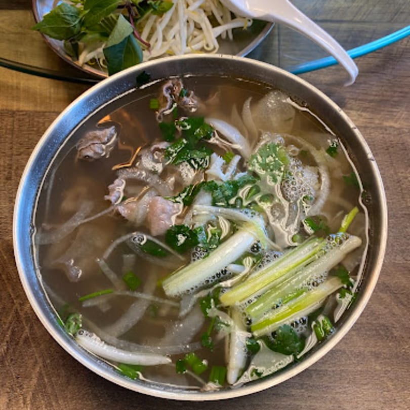 A steaming bowl of Happy Pho Teriyaki's Vietnamese pho with beef, noodles, and fresh herbs.