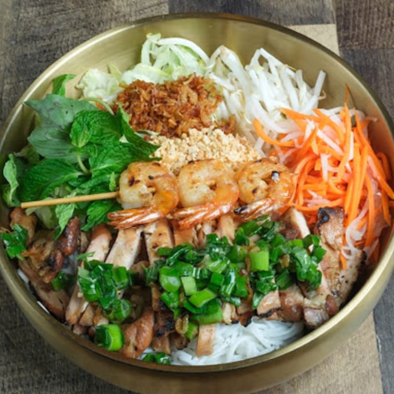 A Vietnamese vermicelli bowl with grilled shrimp, chicken, fresh herbs, and vegetables.